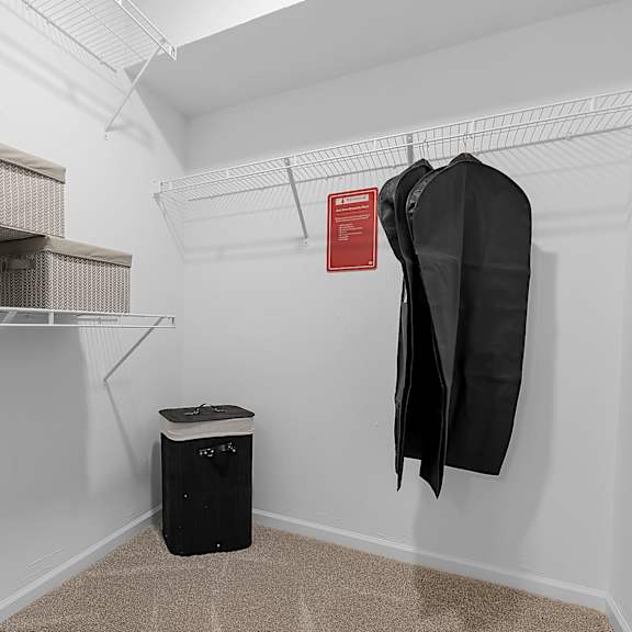 a room with a coat hanging on the wall and a trash can on the floor.