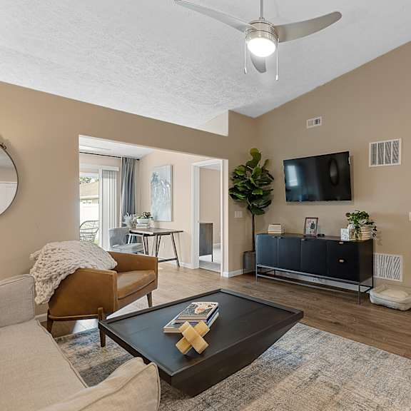 a living room with a brown couch, a coffee table, and a flat screen tv.