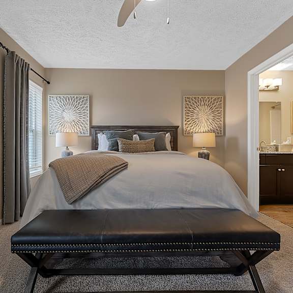 a bedroom with a large bed and a black bench.