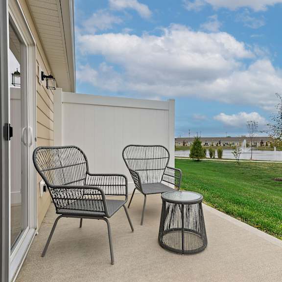 a patio with a chair and table outside a house.