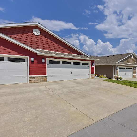 a red building with a white garage door is in front of a house.