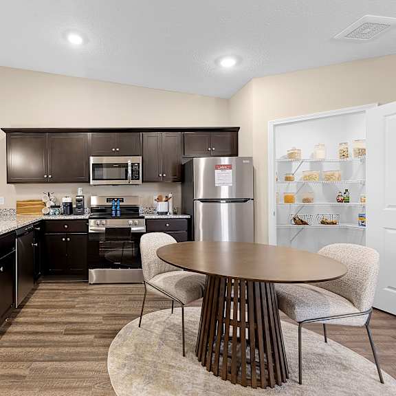 a modern kitchen with dark brown cabinets and a wooden table.