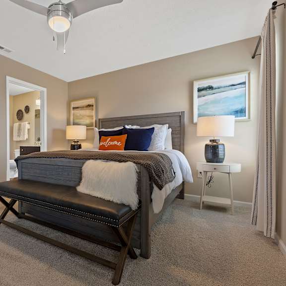 a bedroom with a bed, bench, and a ceiling fan.