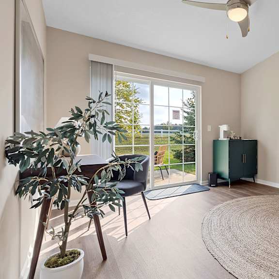 a room with a chair, a table, a potted plant, and a rug.