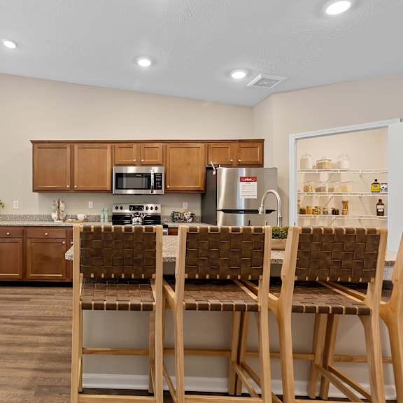 a kitchen with brown chairs and wooden cabinets.
