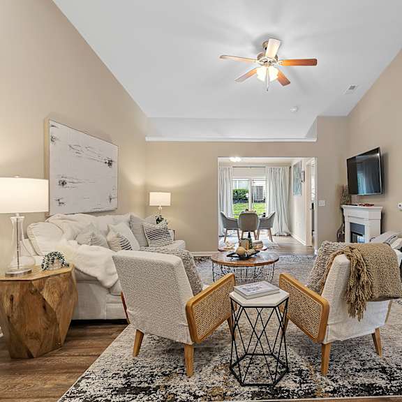 a living room with a white sofa, a wooden coffee table, and a ceiling fan.