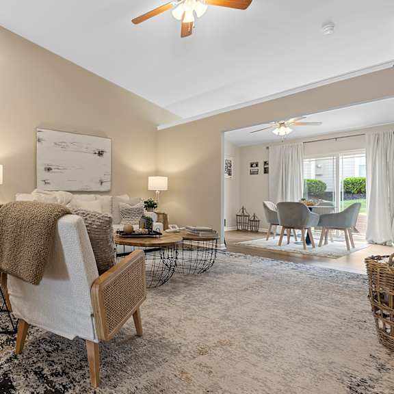 a well-lit, spacious living room with a white sofa and a wooden chair.