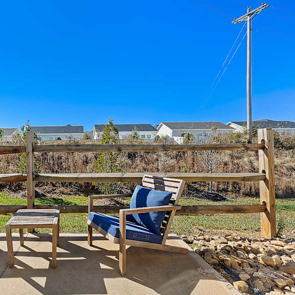 a wooden bench with blue cushions is placed on a patio.