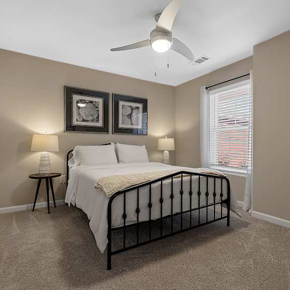 a bedroom with a bed, two lamps, and a ceiling fan.