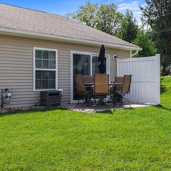a house with a white fence and a patio with chairs.