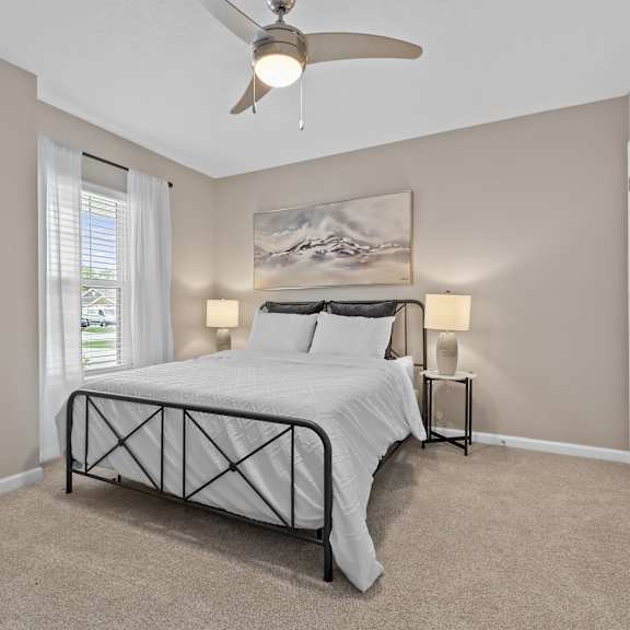 a bedroom with a bed, nightstands, and a ceiling fan.