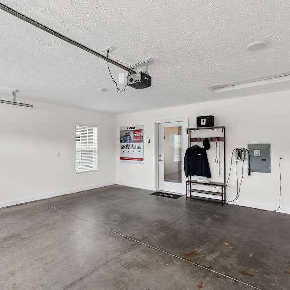 a room with a concrete floor and white walls has a black jacket hanging on a rack.