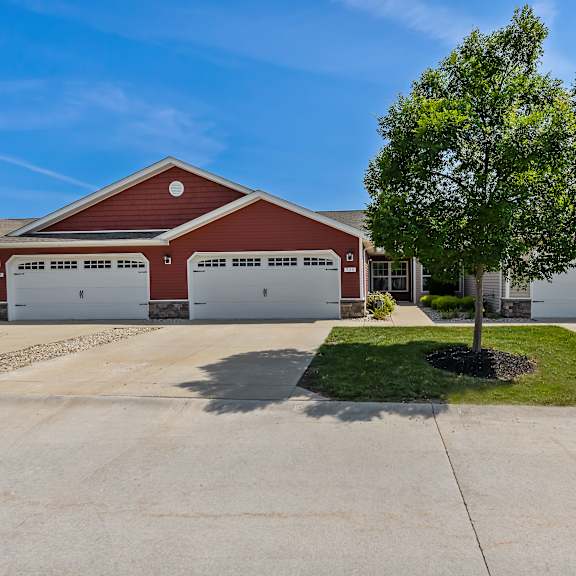 a red and white garage with a tree in front.