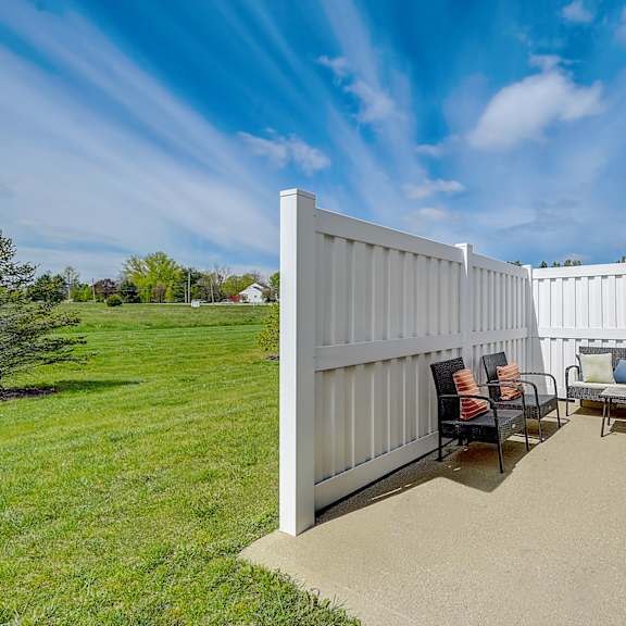 a white fence with a patio and chairs.