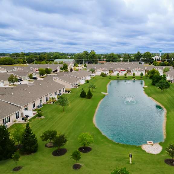 a large swimming pool is surrounded by grass and trees in a residential area.