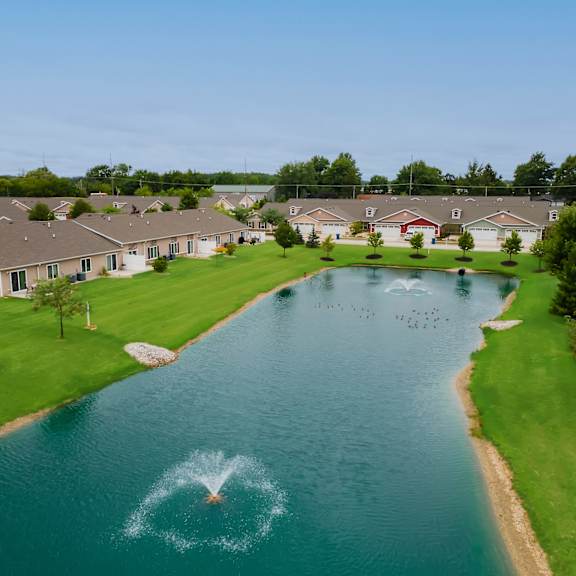 a fountain in the middle of a pond in a residential area.