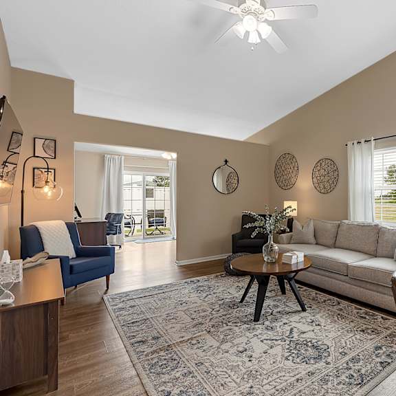 a living room with a blue couch, a coffee table, and a dining table.