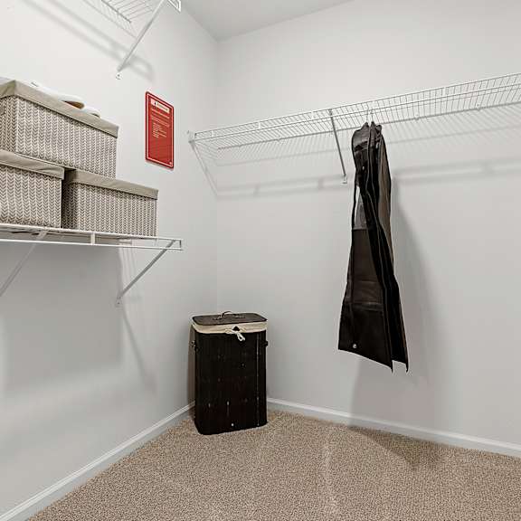 a room with a coat hanging on a rack and a trash can.