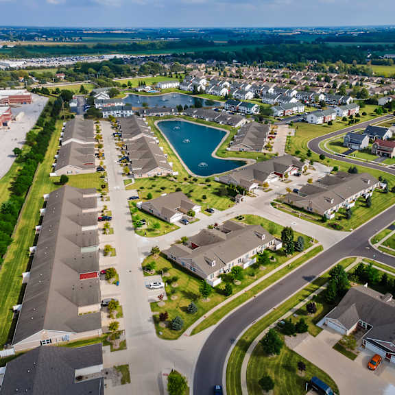 a bird's eye view of a residential area with houses, roads, and a pond.
