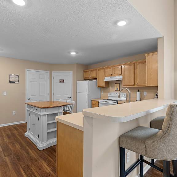 a kitchen with a white island and wooden floors.