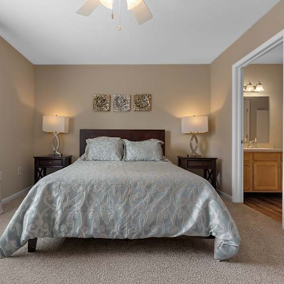 a bedroom with a bed, two lamps, and a ceiling fan.