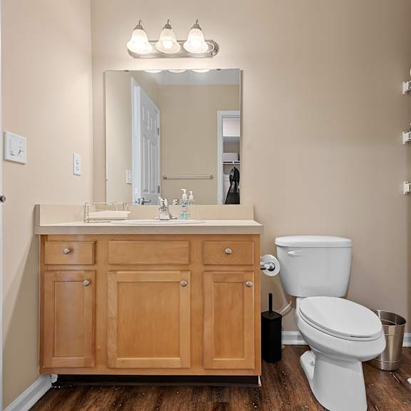 a bathroom with a toilet, sink, and wooden cabinets.