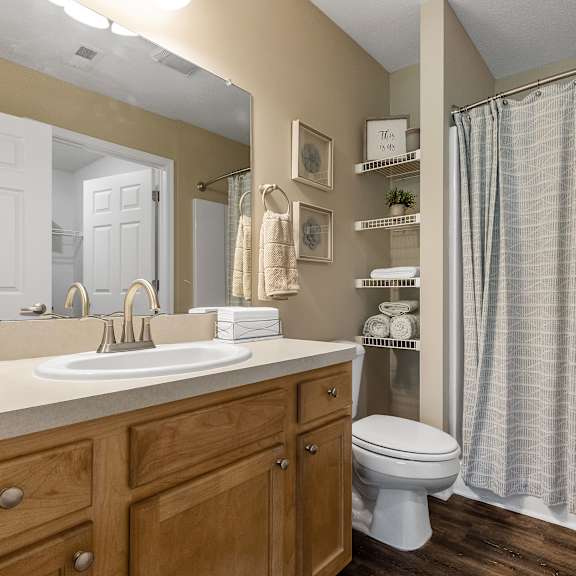 a bathroom with a white sink, wooden cabinets, and a white toilet.