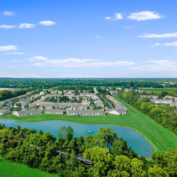 a bird's eye view of a residential area with a lake and greenery.