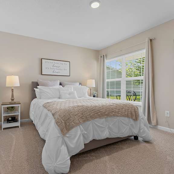 a bedroom with a large bed and a window with blinds.