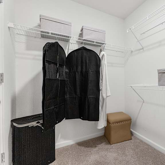 a white closet with a black jacket hanging on the rack.
