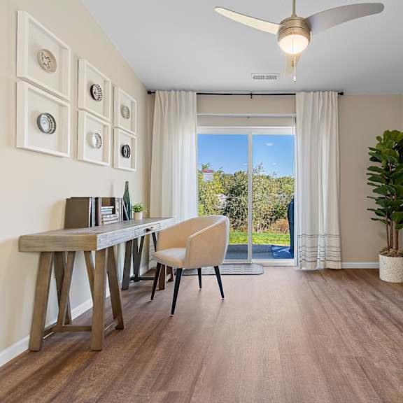 a room with a desk, chair, and a ceiling fan.