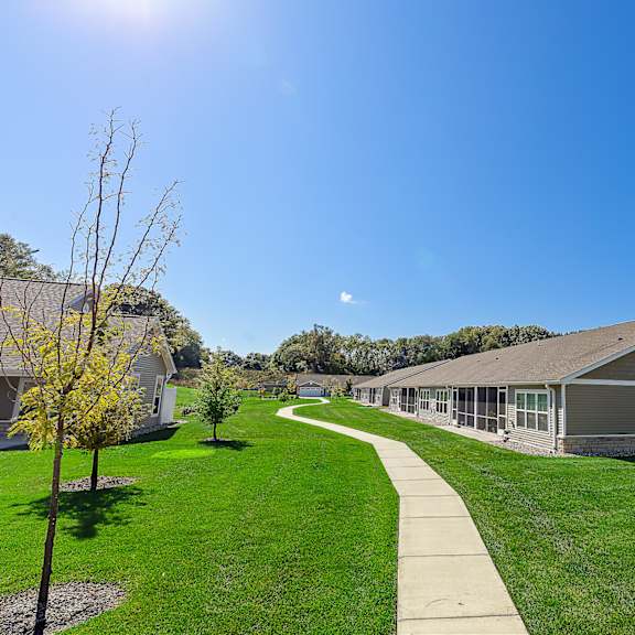 a sunny day at a park with a building and a walking path.