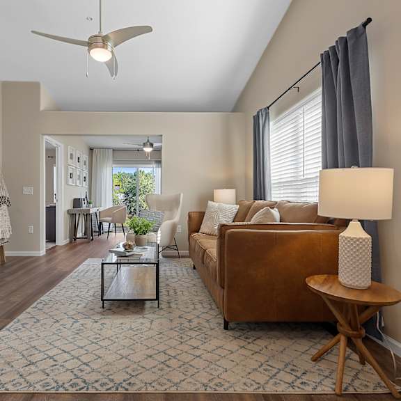 a living room with a brown couch and a ceiling fan.