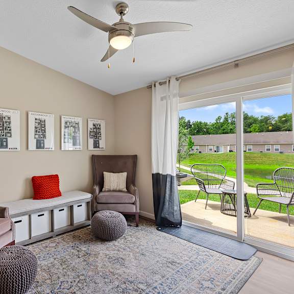 a room with a ceiling fan and a chair with a red pillow.