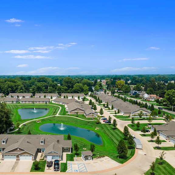 a bird's eye view of a residential neighborhood with houses, a pond, and a playground.