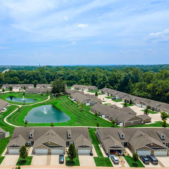 a bird's eye view of a residential neighborhood with houses and a pond.