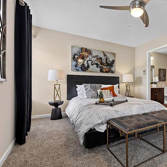 a bedroom with a bed, a bench, and a ceiling fan.