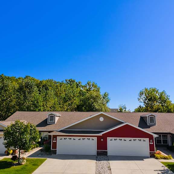 a house with a red garage door is surrounded by greenery.