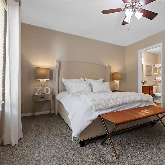 a bedroom with a bed, a bench, and a painting on the wall.