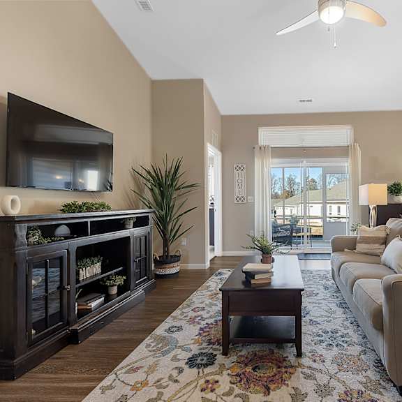 a living room with a large couch, a coffee table, and a flat-screen tv mounted on the wall.