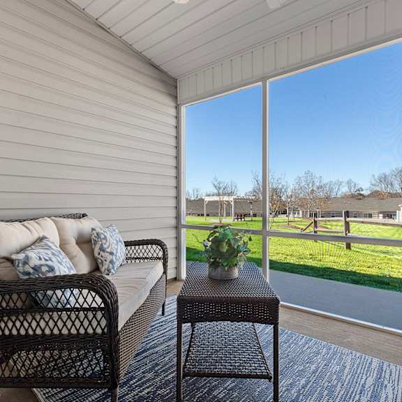 a patio with a sofa and a table with a view of a field.