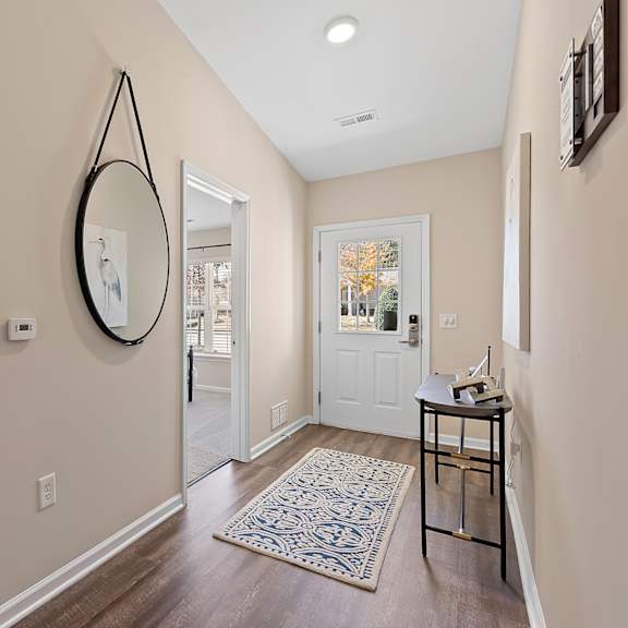 a hallway with a mirror, a table, and a rug.