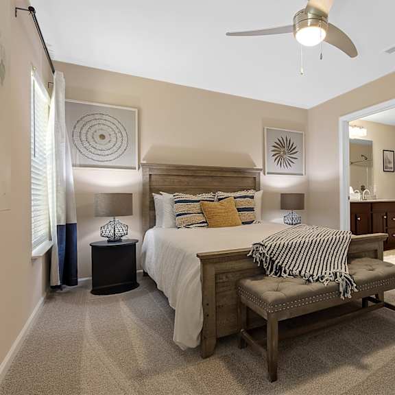 a bedroom with a bed, bench, and decorative wall art.