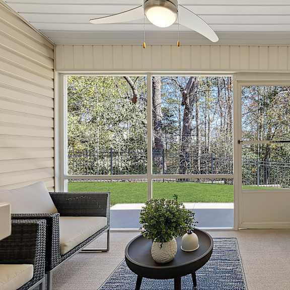 a room with a ceiling fan and a table with a plant on it.
