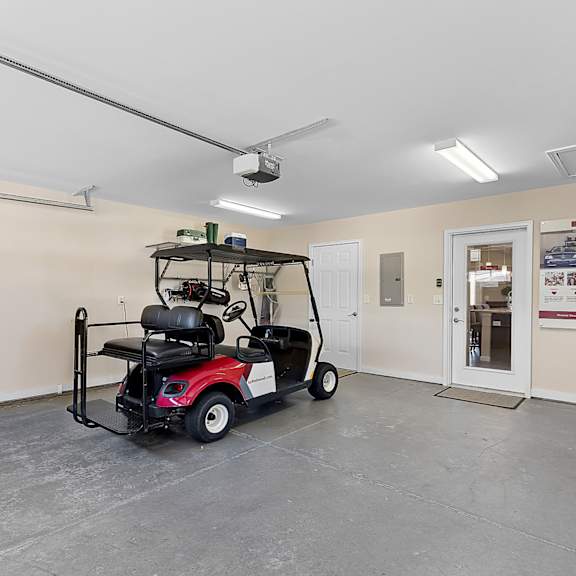 a red and black golf cart is parked in a large room.
