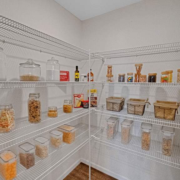 a white pantry with shelves full of jars and containers.