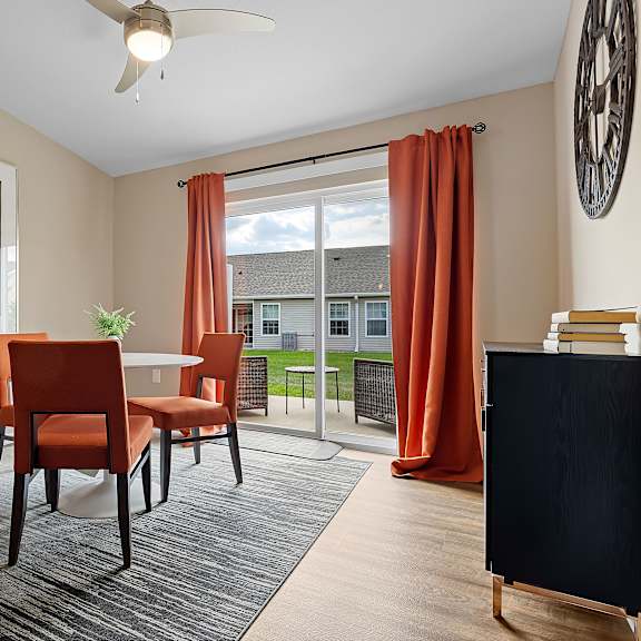 a living room with a ceiling fan, two chairs, a table, and a painting on the wall.