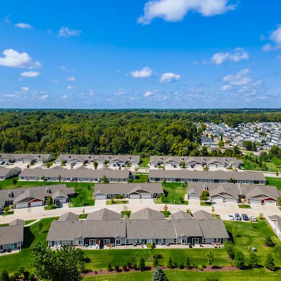 a suburban neighborhood with houses and greenery under a blue sky.
