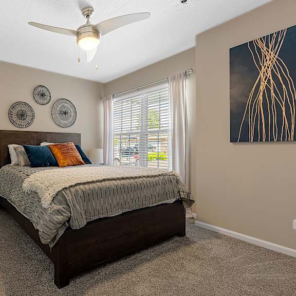 a bedroom with a bed, a ceiling fan, and a window with blinds.