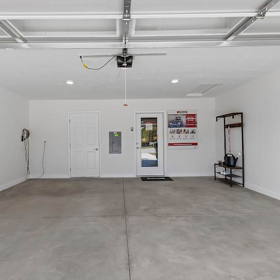 a spacious room with a white ceiling and walls, a grey floor, and a few pieces of furniture.